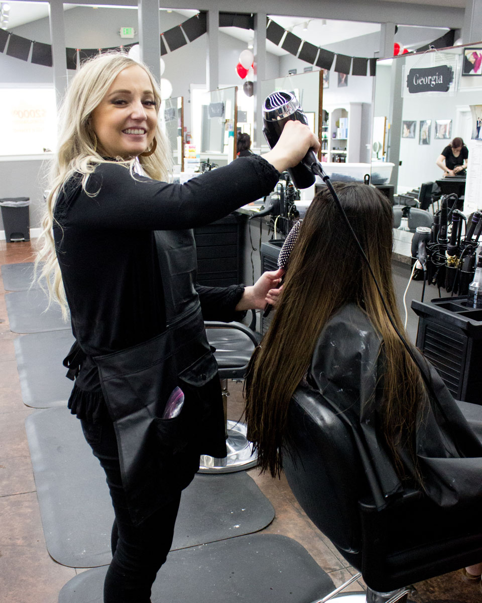 student blow drying a customer's hair after styling it