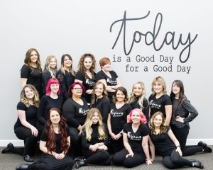 beauty students class photo in front of mural saying "today is a good day for a good day"